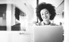 Black-and-white photo of a person using a laptop.