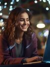 A smiling woman works on her laptop.