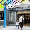 An adult and child walk hand in hand inside Great Ormond Street Hospital for Children.