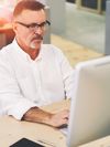 Person in business clothing looks at a desktop computer monitor. 