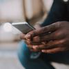 Close-up of a person sitting and holding a cell phone.