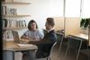 Two colleagues discussing at a desk with a laptop in an office