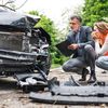 Man and woman examine damage to a car after an accident