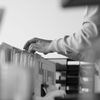 Black and white photo of a person standing at a filing cabinet, rifling through documents.