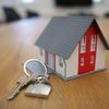 A small model of a house sits near house keys.