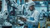 Worker with hard hat in a factory with robotic arms