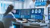Woman neuroscientist surrounded by monitors showing brain scans