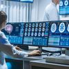 Woman neuroscientist surrounded by monitors showing brain scans