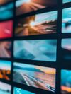 A wall of multiple digital screens displaying colorful images, including abstract grids and bodies of water, arranged in a grid-like pattern.