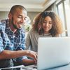 Two people smile at a laptop while one of them submits their application to become a Hylander. 