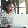 A person sits at their laptop to learn more about how their organization could partner with Hyland.