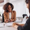 Two people discussing an insurance policy while sitting at a desk in a meeting room.