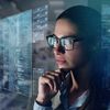 Close up of a woman with glasses while she is working with a computer with holograms.