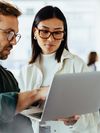 Coworkers discuss what they see on a laptop