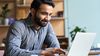 Person sits in office setting at laptop.