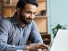 Person sits in office setting at laptop.