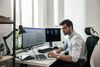 Healthcare worker checks laptop while processing electronic documents.
