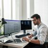 Healthcare worker checks laptop while processing electronic documents.