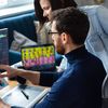 Two people discuss digital assets on a desktop computer.
