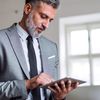 Person in gray suit uses a tablet computer.