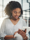 Person stands, smiles and looks at a tablet.