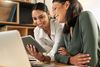 Two businesswomen using a digital tablet to oversee work