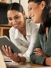 Two businesswomen using a digital tablet to oversee work