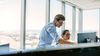 Two coworkers look at dual screens and strategize about future AI projects.