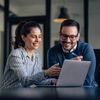 Two coworkers in office setting discussing BPA strategy on work laptop