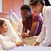 Child in a hospital bed with nurse and caregiver