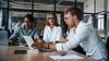Young professionals sit at a conference table.
