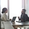 Two people discuss business in an office conference room.