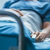 Patient sits in a hospital bed with a finger monitor on.