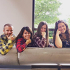 Five people wearing flannel shirts pose while smiling.
