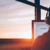 Person wearing headphones works at a computer near a window.
