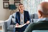 Mature social worker talking to senior man and taking notes