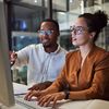 Two employees sit at a desktop computer and review Hyland capabilities on a monitor.?