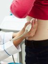 A healthcare professional uses an ultrasound device on a patient?s left side.