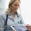 Clinician holding a digital tablet pointing to a medical image.