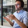 A managed services expert sits at a desk with a headset and collaborates virtually with a customer.