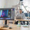 Graphic designer works on a computer in an open office setting.