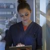 Medical professional wearing scrubs enters data on a tablet computer.