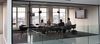 Four people sit in a glass conference room.