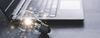 Light bulb with sparks around it sits near a laptop.