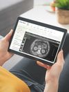 Person holds a digital tablet that displays abdominal imaging via a patient portal. 