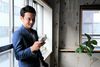 Person leans against window holding a cell phone.