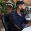 Person sits at desktop computer with houseplants on desk.