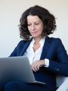Businessperson sits at a chair with a laptop.