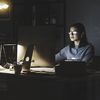 Person sits in a dark office working on their computer.