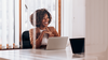 Person sits in office conference room in front of laptop.